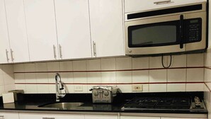 A kitchen with white cabinets, a stainless steel sink, a microwave, and a gas stove. - New Beautiful 2 bedroom full Apartment San Juan, Area Metro. (San Juan)