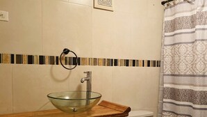 A bathroom with a wooden vanity, a glass bowl sink, a toilet, and a shower curtain. - New Beautiful 2 bedroom full Apartment San Juan, Area Metro. (San Juan)