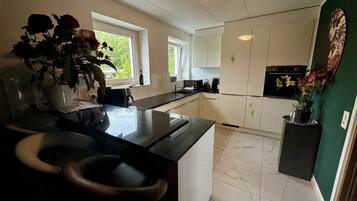 Una cocina moderna con una isla central, muebles blancos y una pared de acento verde.