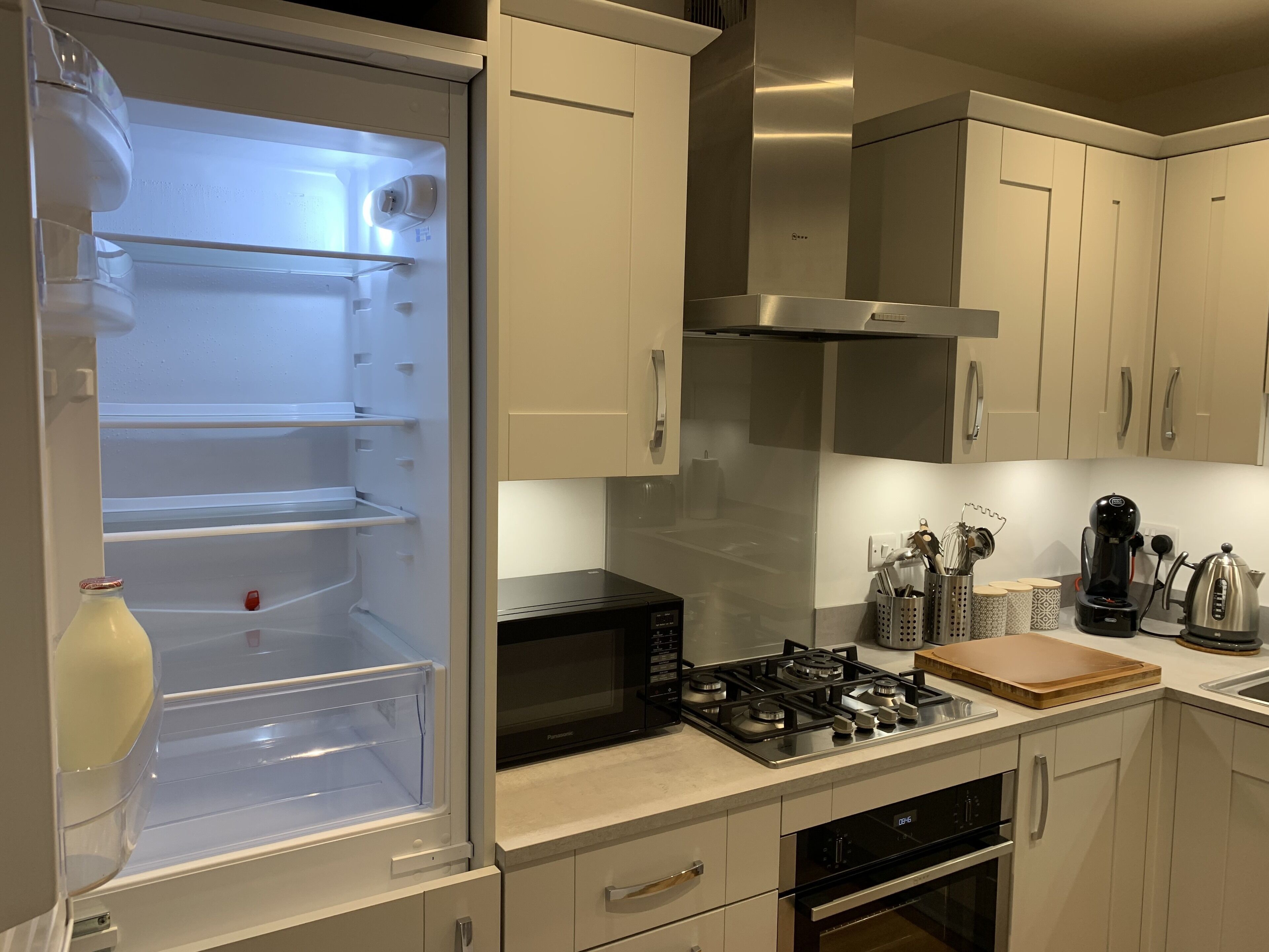 Une cuisine moderne équipée d’un réfrigérateur encastré, d’un four à micro-ondes, d’une cuisinière à gaz, d’un four et de meubles de rangement en acier inoxydable.