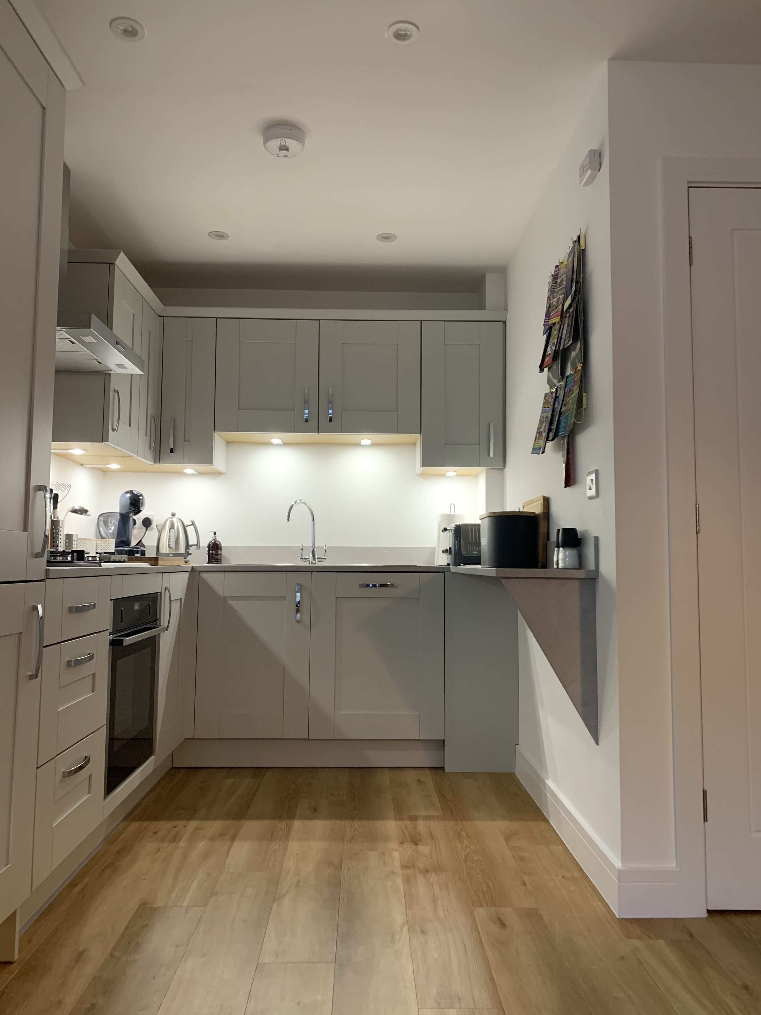 A modern kitchen with grey cabinets, a built-in oven, and a microwave.