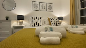 A neatly arranged hotel room with a bed, two bedside tables, a mirror, and framed artwork on the wall. - A stroll to Ringwood, near to New Forest & South Coast Beaches. Private Parking (Ringwood)