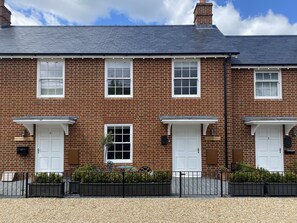 A two-story brick house with white doors and windows, a gravel driveway, and a black metal fence. - A stroll to Ringwood, near to New Forest & South Coast Beaches. Private Parking (Ringwood)