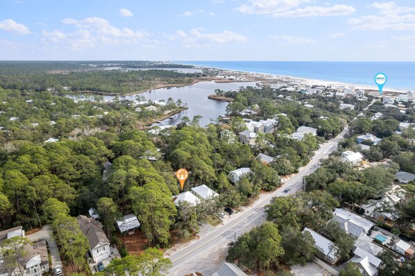 An aerial view of a coastal residential area with houses, a lake, and a beach.