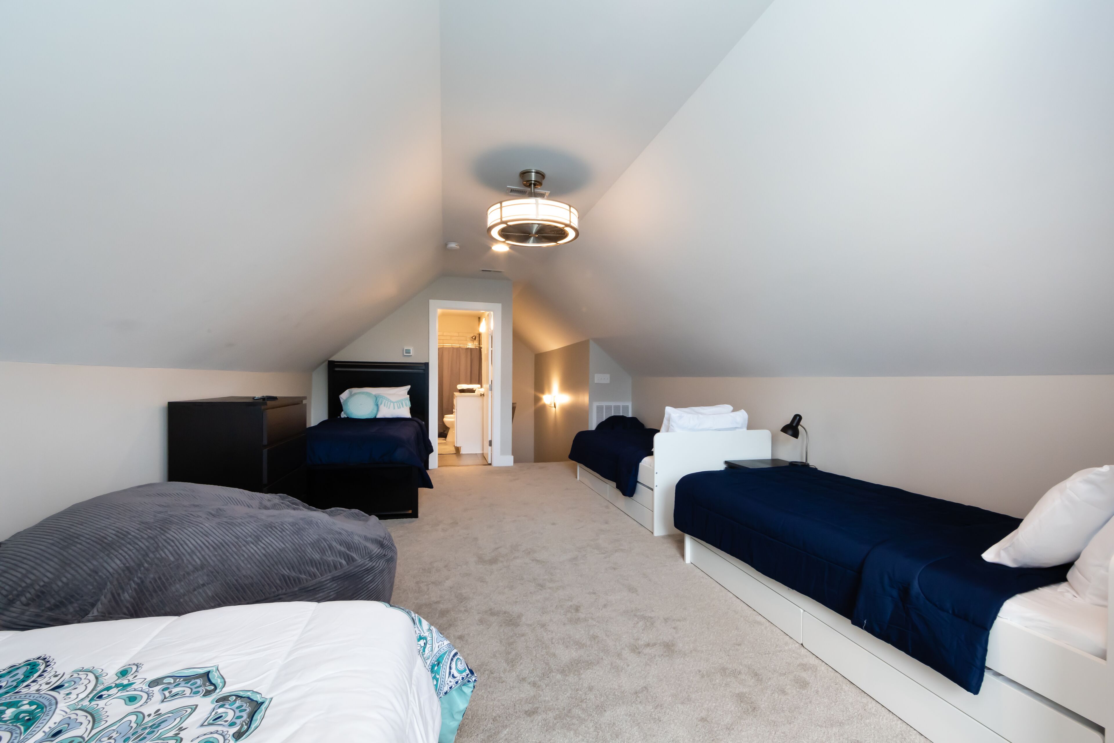 A small, well-lit attic bedroom with two beds, a desk, and a walk-in closet.
