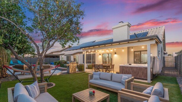 Un jardin avec une terrasse, du mobilier d’extérieur, un espace barbecue et un arbre.