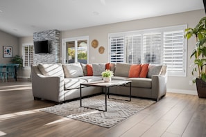 A modern living room with a sectional sofa, a coffee table, and a fireplace.