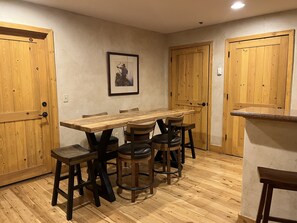 Un comedor con una mesa y sillas de madera, un cuadro enmarcado en la pared y puertas de madera.