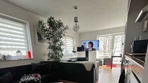 Un salon moderne avec un canapé noir, une table basse blanche, un tapis rouge et un tapis abstrait aux couleurs vives.