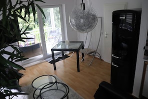 Relax in this stylish living space with a glass-top dining table, black metal frame, and sliding glass door leading to a balcony.
