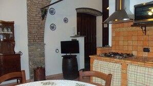A kitchen with a tiled backsplash, a stove, and a television on a stand. - The Tralcio, beautiful! (Garlenda)