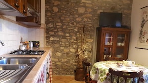 Eine Küche mit Steinwand, Spüle, Herd und Essbereich mit Tisch und Stühlen.