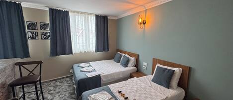 A hotel room with two beds, a desk, and a chair.