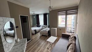 Moderni hotellihuone, jossa on marmorilla verhoiltu kylpyhuone, sohva, pieni pöytä ja parveke, jolta on näkymä.