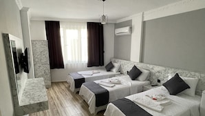 Hotellihuone, jossa on kaksi sänkyä, marmorilaatoitettu lattia, sisäänrakennettu televisio ja ilmastointilaite.
