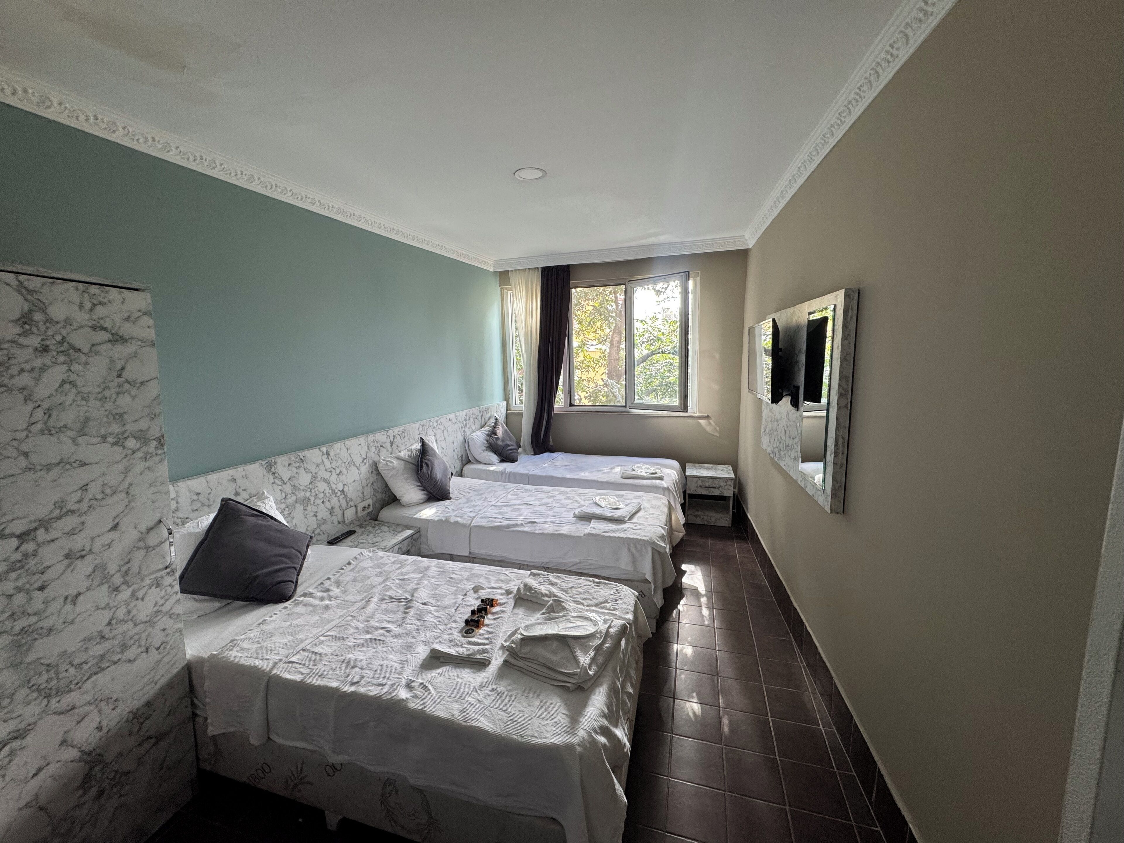 Habitación de hotel con dos camas, un televisor en la pared y una ventana con cortinas.