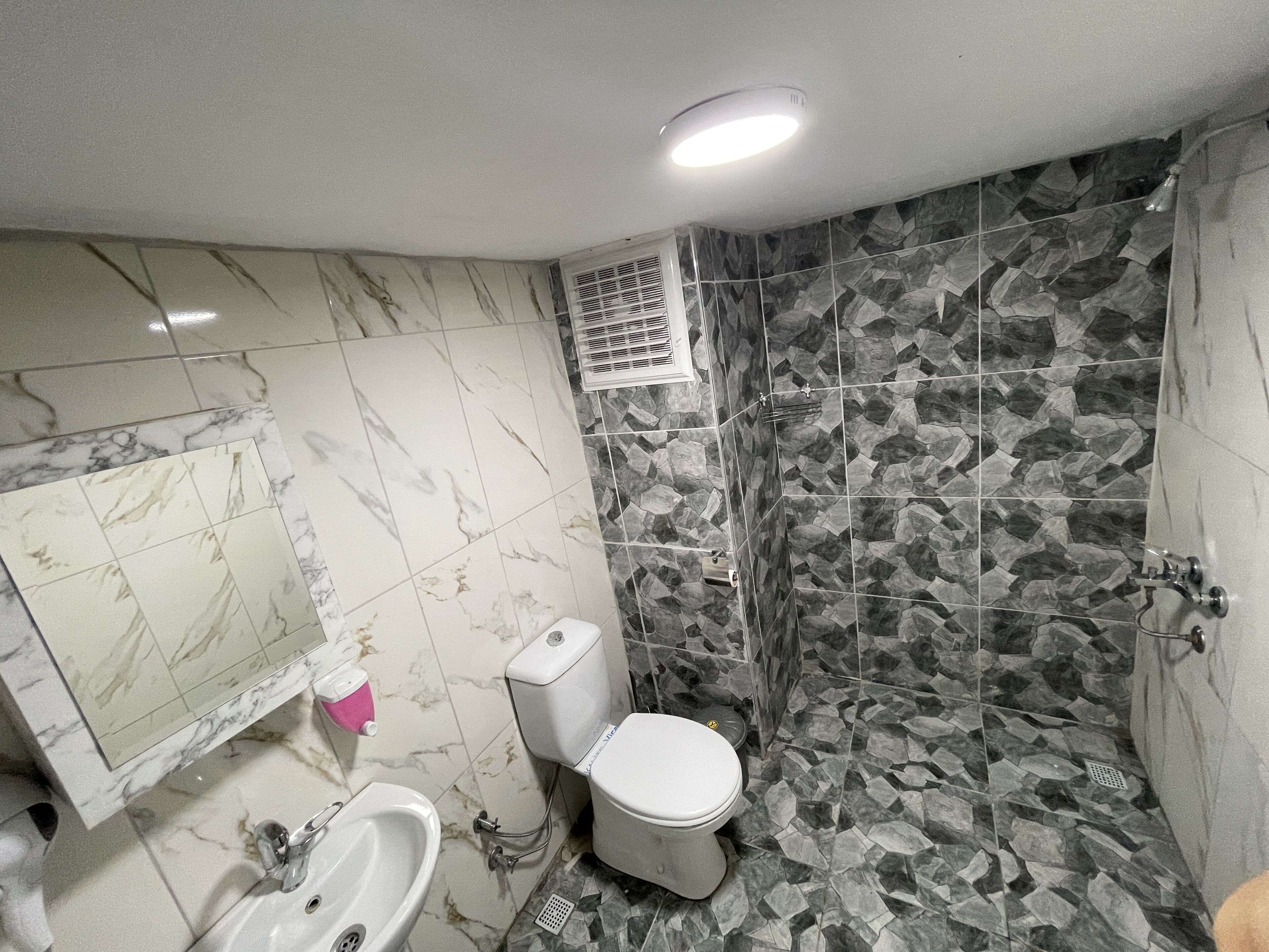 A bathroom with a toilet, sink, and shower area.