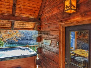 A wooden cabin with a hot tub, a welcome sign, and a view of a lake. - Luxury Lake House w/Private Dock, Pontoon Boat, Hot Tub, Pool Table, Theatre Rm (Topton)