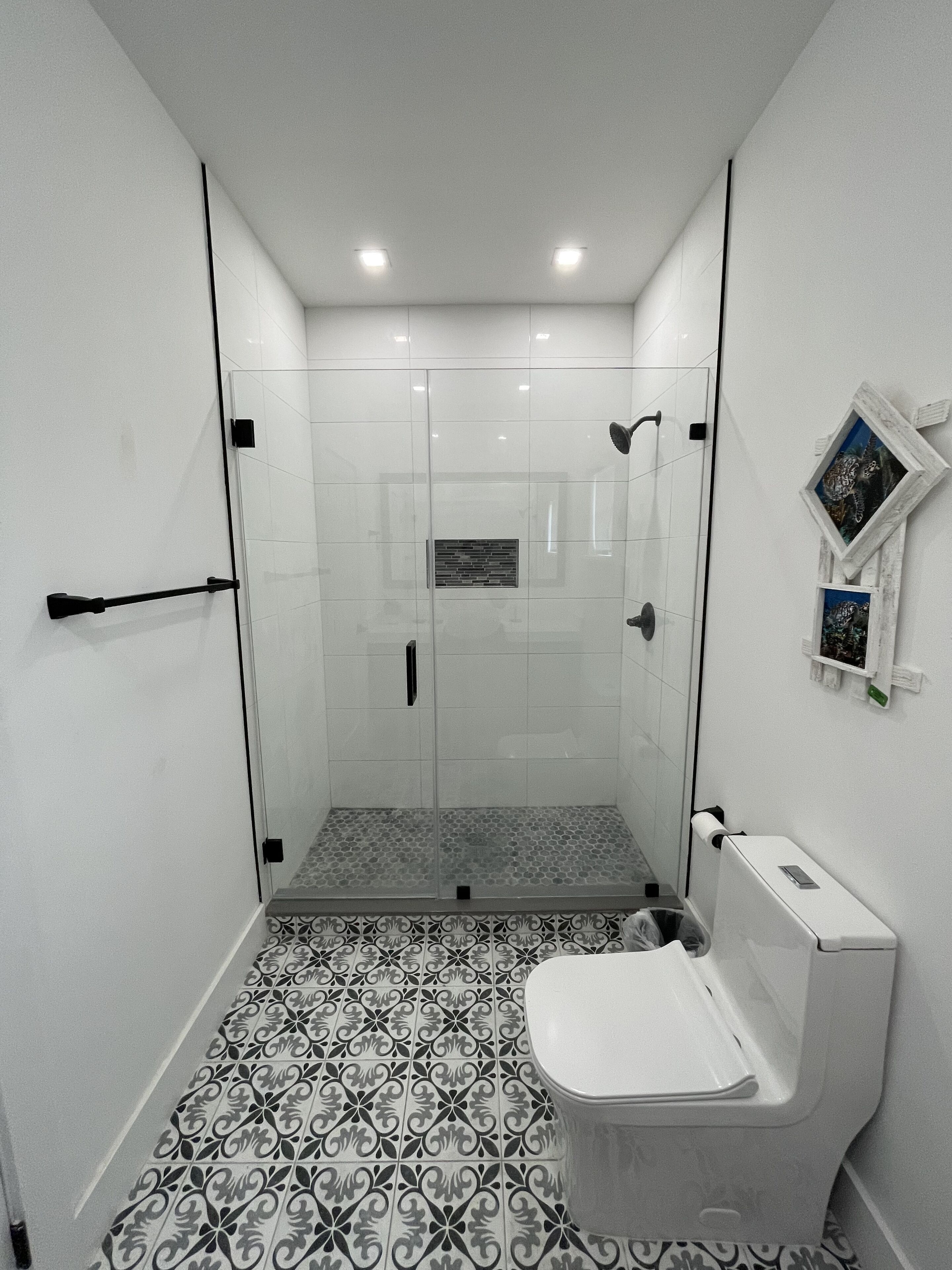 A bathroom with a shower, toilet, and a patterned floor.