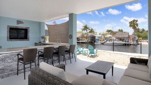 Un espace extérieur abrité comprenant un bar, des sièges et une vue sur un port de plaisance.