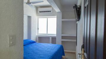 Ein Schlafzimmer mit Bett, Fenster, Deckenventilator und integrierten Regalen.