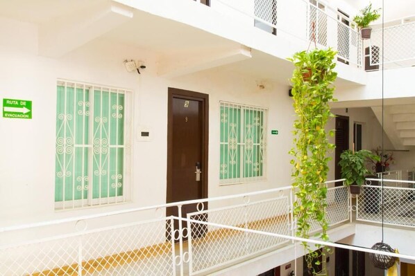 A multi-level building with balconies, a green sign indicating an evacuation route, and a door marked with the number 9. - Hotel Acapulco (Acapulco)