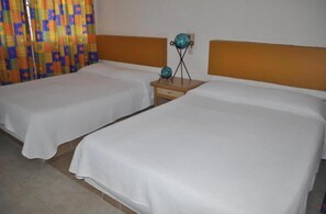 A hotel room with two single beds, a wooden nightstand, and a decorative globe. - Hotel Acapulco (Acapulco)