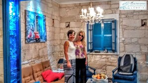 A room with stone walls, a chandelier, a sofa, and a table with fruit.