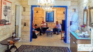 A room with stone walls, a chandelier, a blue-framed doorway, and a table with people sitting.