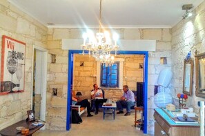 A room with stone walls, a chandelier, a blue-framed doorway, and a table with people sitting.