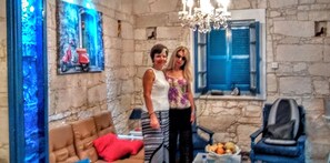 A room with stone walls, a chandelier, a sofa, and a table with fruit.