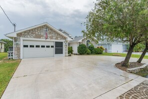 Une maison à deux étages avec une façade en pierre, un garage et une pelouse bien entretenue.
