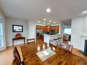 Ein geräumiger Essbereich mit Holztisch und Stühlen, eine Küche mit Holzausstattung und ein Wohnbereich mit Sofa und Kamin.
