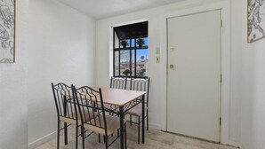 Un coin repas comprenant une table et quatre chaises, une fenêtre à cadre noir et une porte fermée.