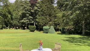 A well-maintained lawn with neatly trimmed hedges and a table with a vase of flowers. - New - Luxury Spacious Apartment in Beautiful Grounds (Oswestry, Shropshire)