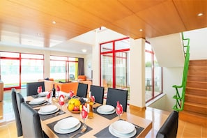 A dining area with a long table set for a meal, surrounded by chairs.