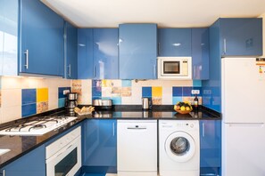 A modern kitchen with blue cabinets, a microwave, a coffee maker, a toaster, and a washing machine. - Villa with heatable pool & BBQ in Albufeira Marina (Albufeira)