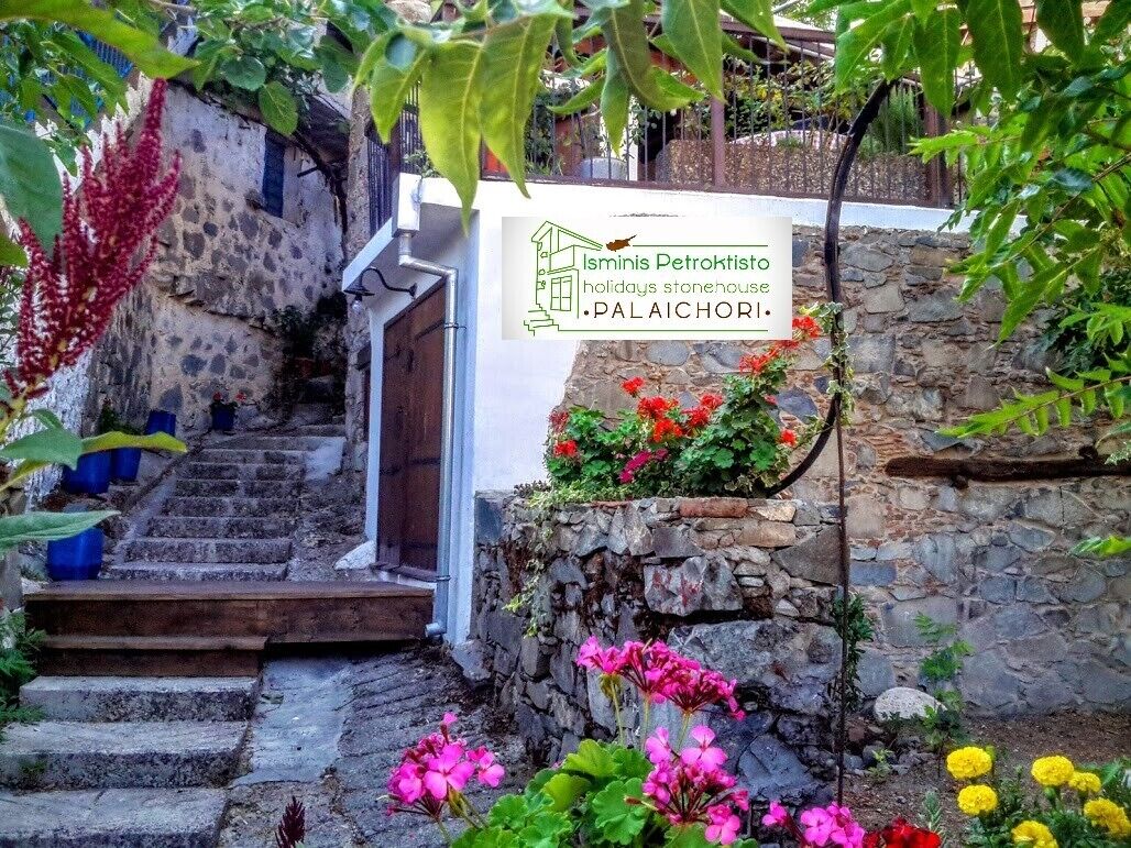 Una scala in pietra conduce a una porta con una targa che indica Ismimis Petrokristo case vacanze Palaichori.