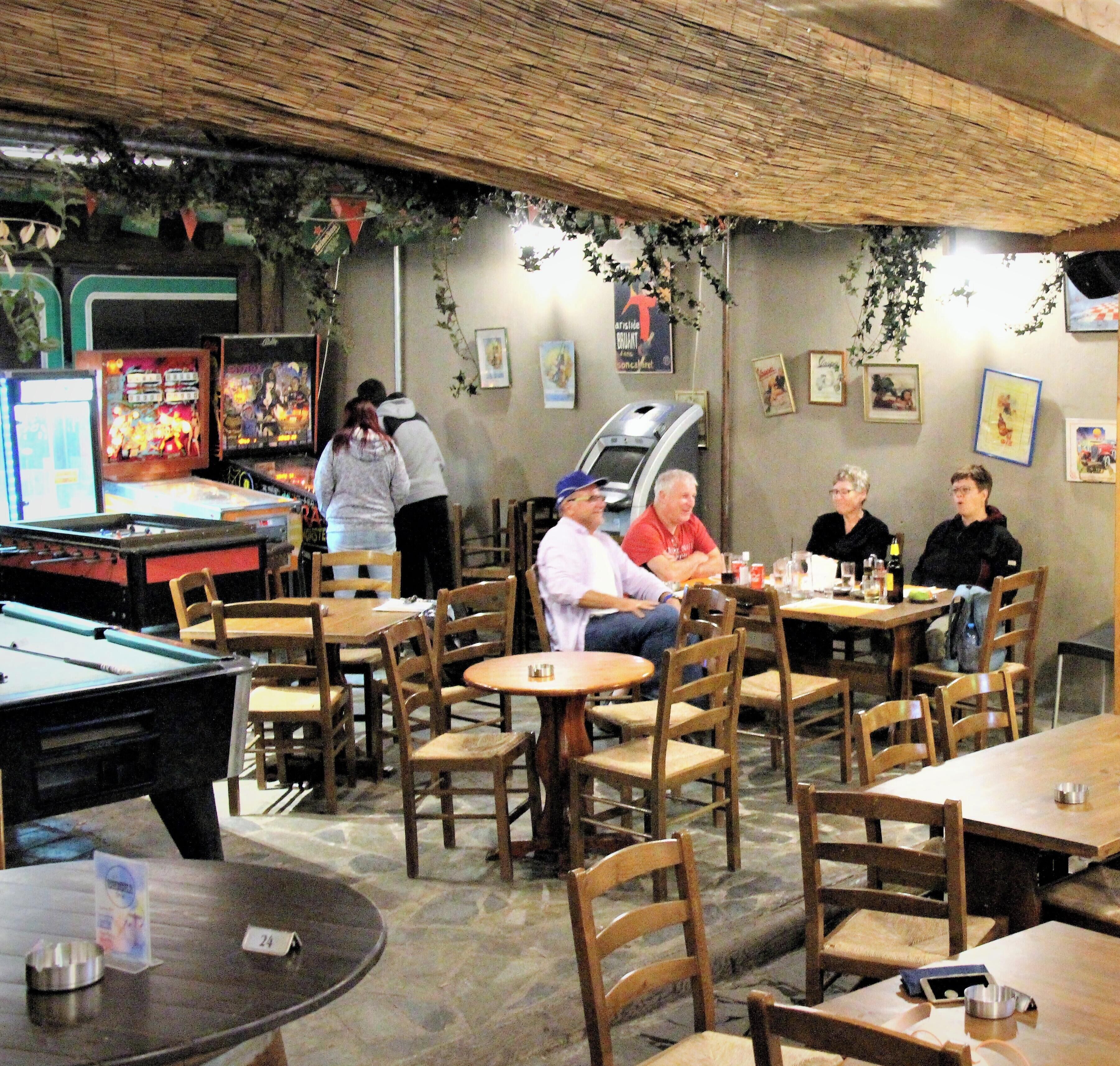 Un'accogliente sala da pranzo interna con tavoli e sedie di legno, un tavolo da biliardo e giochi arcade.