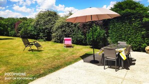 An outdoor patio area with a table and chairs, a picnic table, and a large umbrella. - Gîte la bocagere  (Autreppes)
