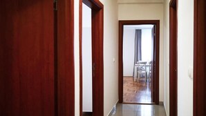 A hallway with wooden doors leading to a dining area with a table and chairs.