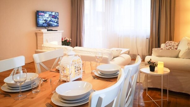 A well-lit living room with a dining area, a fireplace, a television, and a sofa.