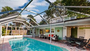 A covered outdoor swimming pool with a patio area, including seating and a table. - Designer Home on a Canal (Siesta Key)