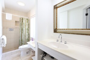 Un baño con inodoro, lavamanos y zona de ducha.