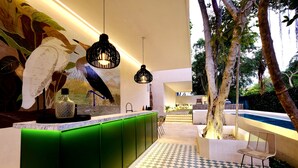 Cozinha moderna com armários verdes, luminárias pendentes e chão quadriculado.