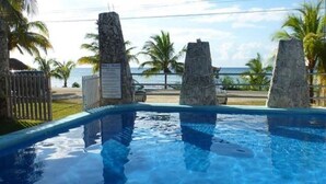 A swimming pool with stone pillars, a view of the beach, and palm trees. - Private Guest Villa - Two Bedroom - Full Kitchen - Ocean Front Villa Cozumel (San Miguel de Cozumel)