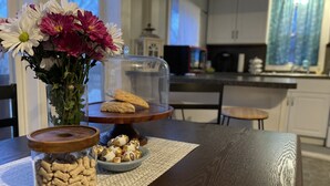 A kitchen with a wooden table displaying cookies, chocolates, and a vase of flowers. - Pet Friendly Home by Lake Shawnee! (Topeka)