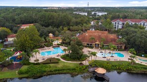 Un resort con varias piscinas, un lago y exuberante vegetación circundante.