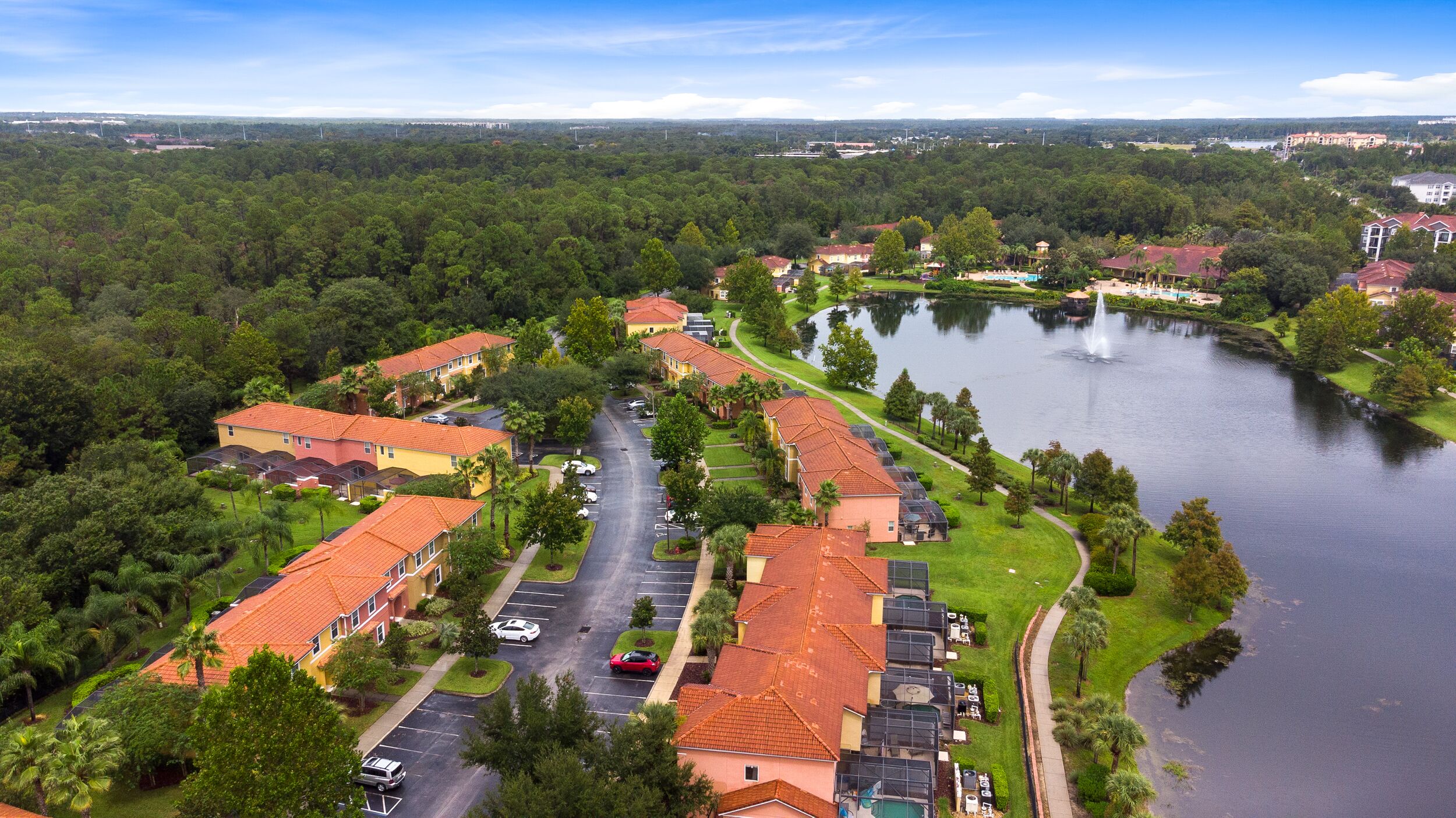 A residential area with houses along a curved road, a body of water, and a distant view of a city skyline.
