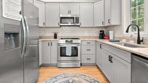 Una cocina moderna con electrodomésticos de acero inoxidable, gabinetes blancos y un amplio ventanal que proporciona luz natural.